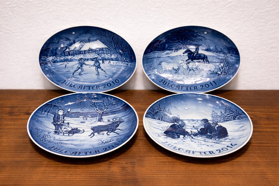 Royal Copenhagen Christmas plates (Jule Aften series) 2010, 2011, 2014, 2015: Set of 4 Royal Copenhagen Christmas plates from 2010, 2011, 2014, and 2015. Each plate features detailed winter and holiday scenes in classic cobalt blue porcelain and is part of the well-known Jule A