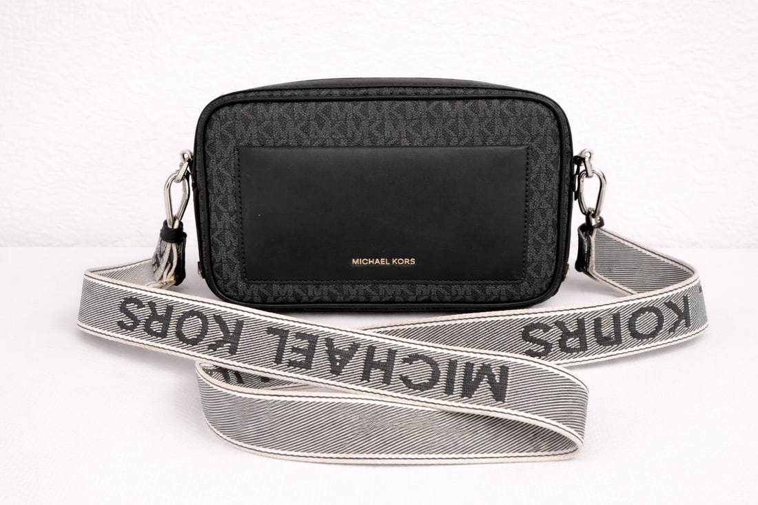 Michael Kors crossbody bag: Michael Kors crossbody bag featuring signature MK monogram canvas with black leather trim and front pocket. Includes adjustable wide logo strap. Compact camera bag style, perfect for everyday use.