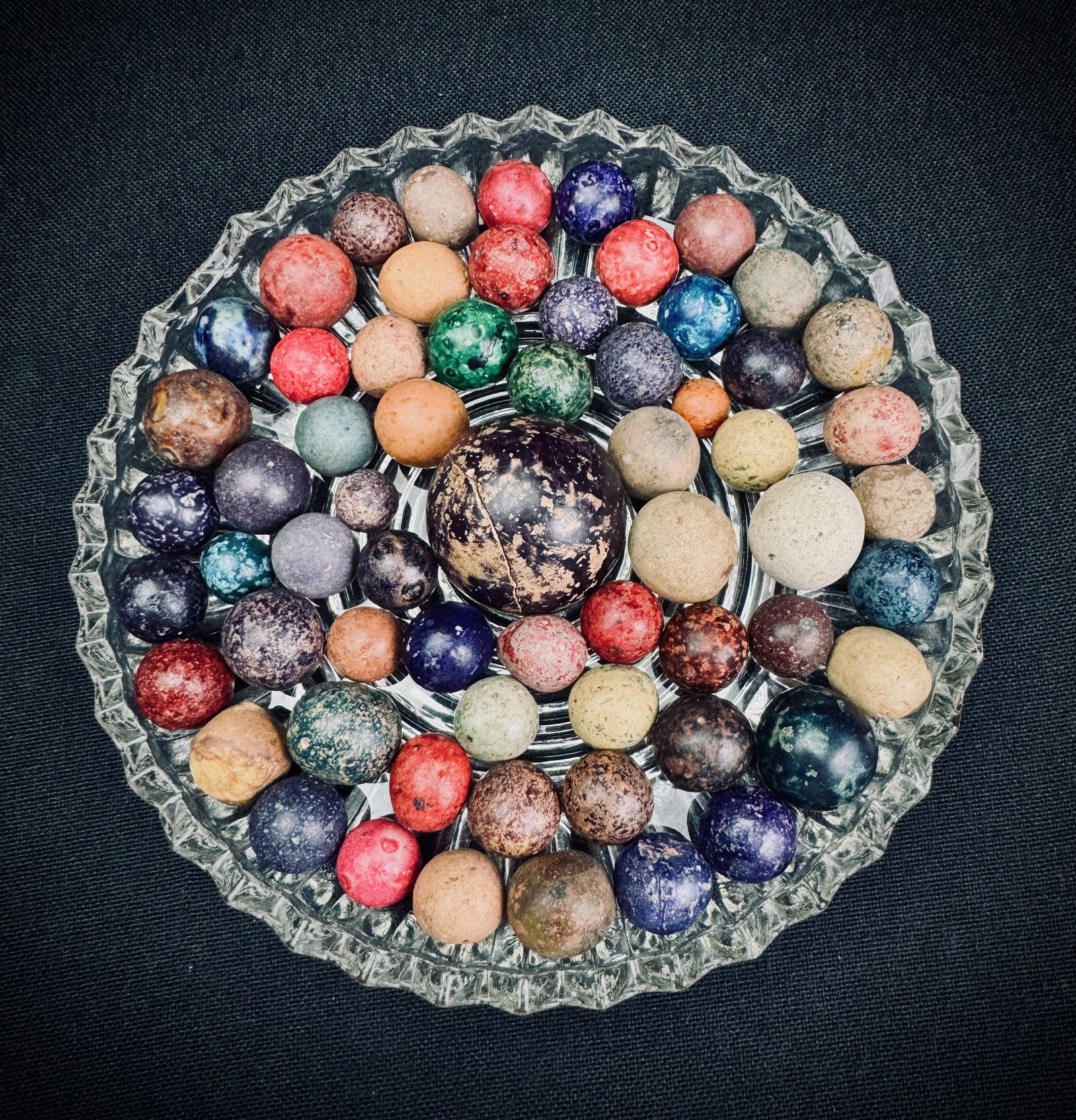 Large Lot of Antique Clay Marbles with Shooter: This lot features a large collection of vintage unglazed clay marbles in various colors and sizes. Included is one large shooter marble, approximately 1.3 inches in diameter. The collection includes d