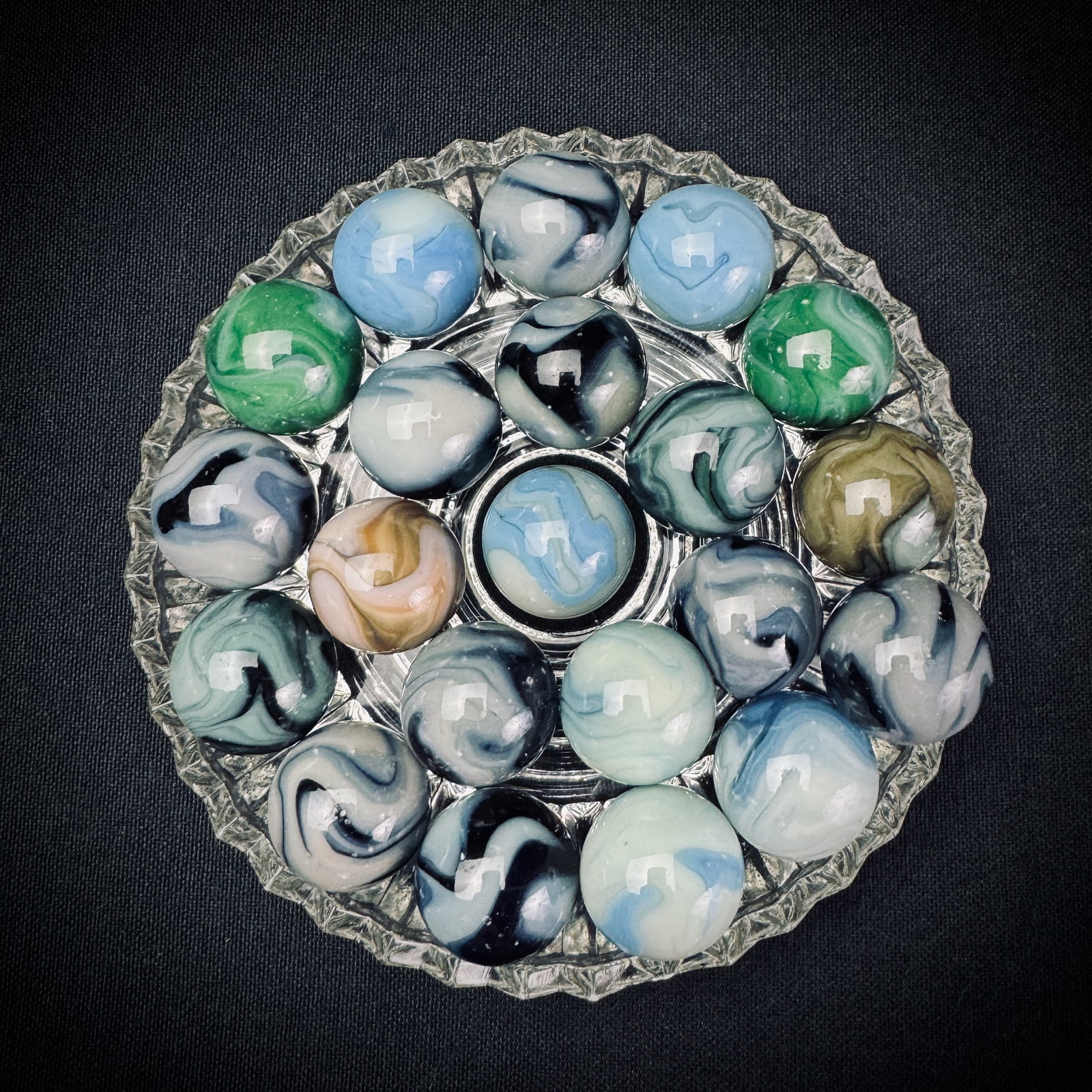 Lot of Vintage Glass Slag & Swirl Marbles: This is a lot of over twenty glass marbles. The marbles feature various colors including blue, green, black, and brown swirled into an opaque white or translucent base. Each marble measures approximat