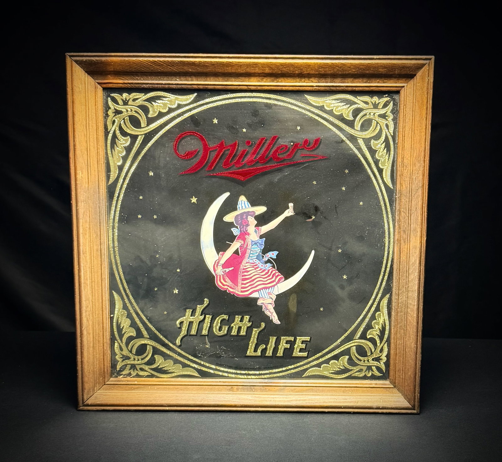 Miller High Life 'Girl on the Moon' Mirror: This is a Miller High Life advertising mirror. The piece features the iconic "Girl on the Moon" imagery against a starry black background. The design is accented with a gold-tone filigree border and r