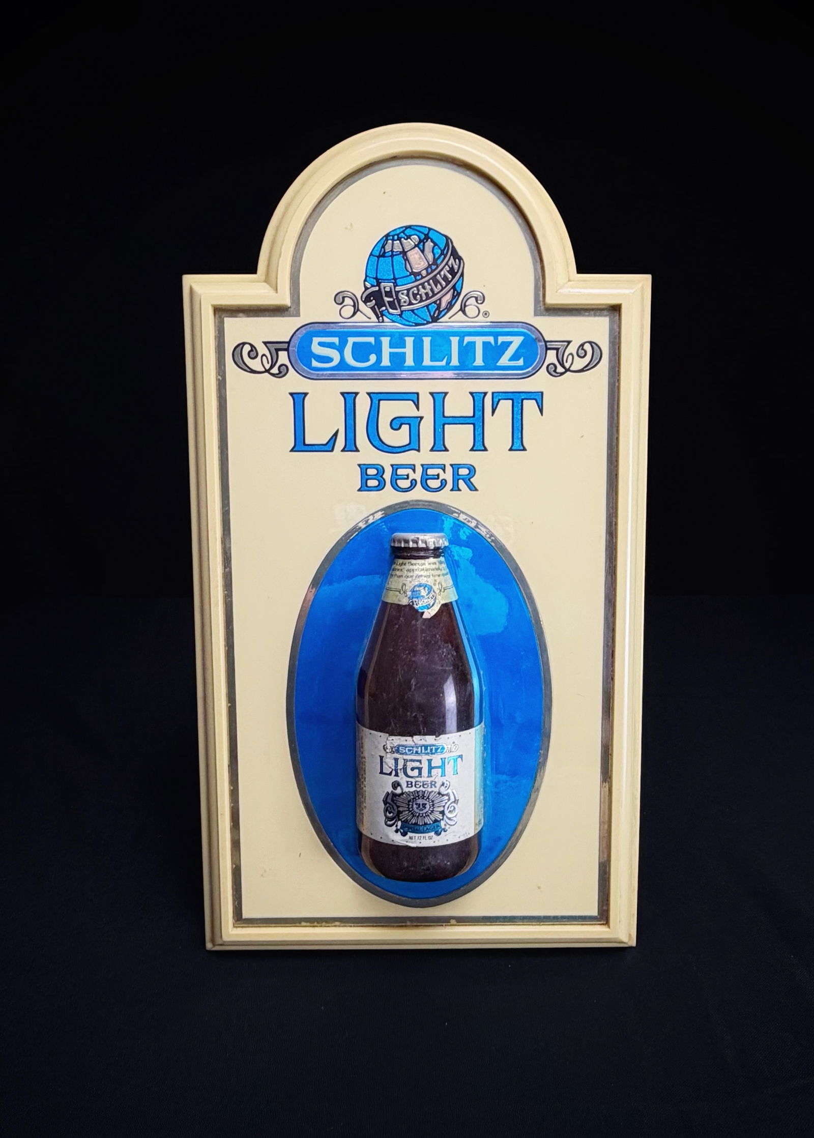 Vintage Schlitz Light Beer 3D Wall Sign: This is a vintage Schlitz Light Beer advertising sign. The piece is constructed from molded plastic and features a three-dimensional bottle element in the center. The sign displays the classic Schlitz