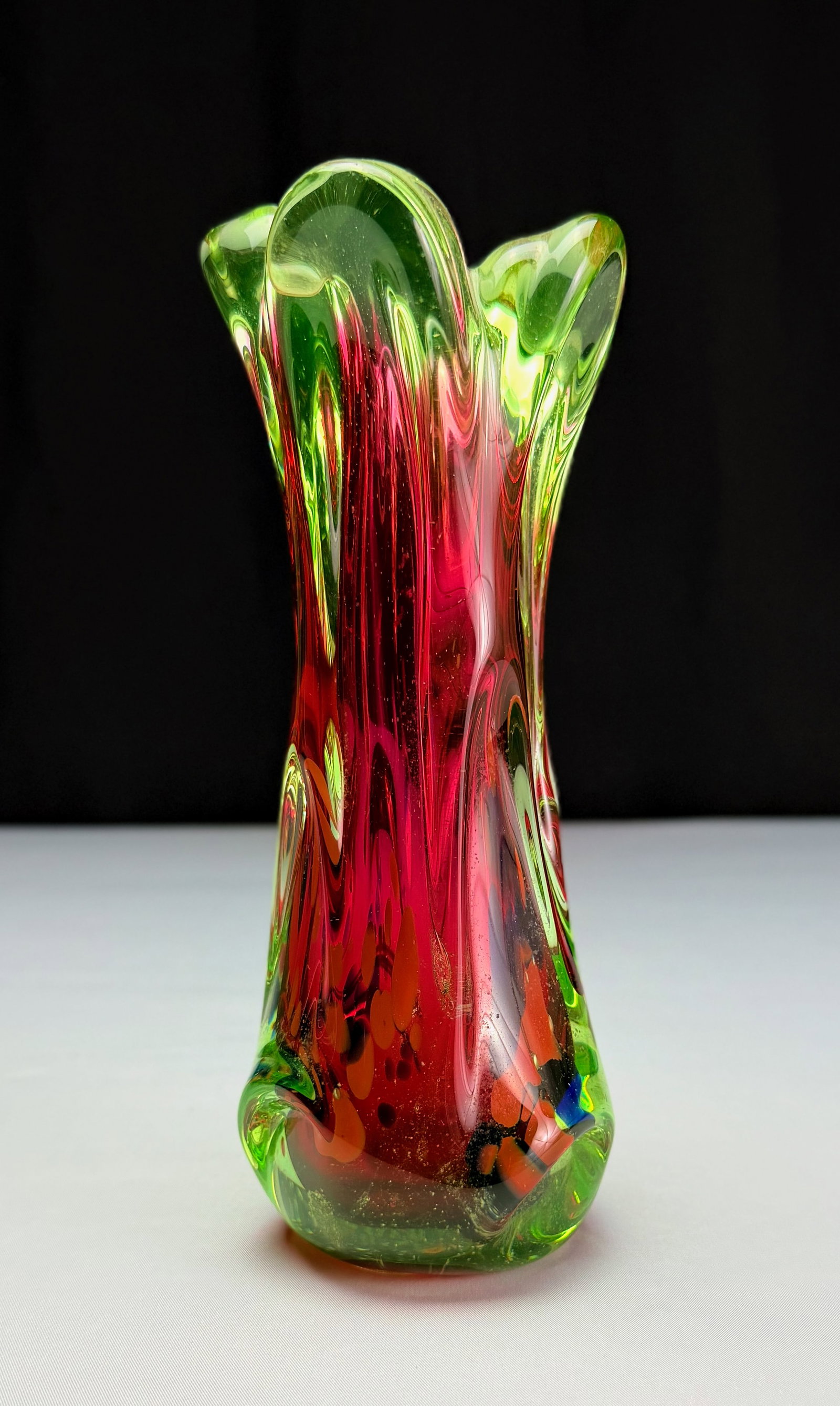 Mid-Century Modern 'Watermelon' Art Glass Vase: A striking mid-century modern art glass vase featuring a stretched, fluted form. The vibrant glass displays a dynamic combination of green and red, creating a 'watermelon' effect. Internal details inc