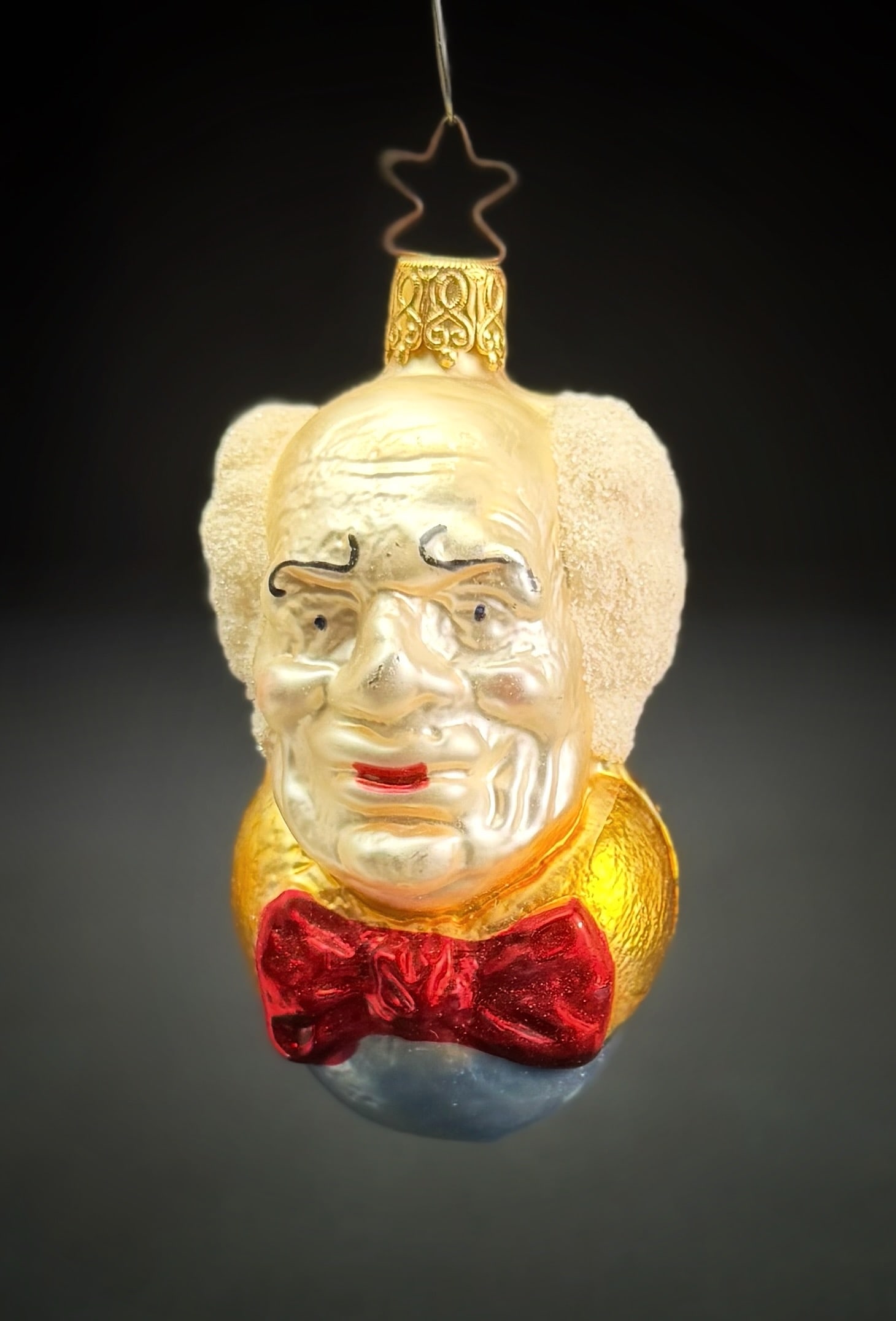 Inge Glas West Germany Wizard of Oz Ornament: A vintage hand-blown glass Christmas ornament produced by Inge Glas in West Germany. The piece is molded in the form of the Wizard of Oz, featuring painted facial details and flocked hair. The ornamen