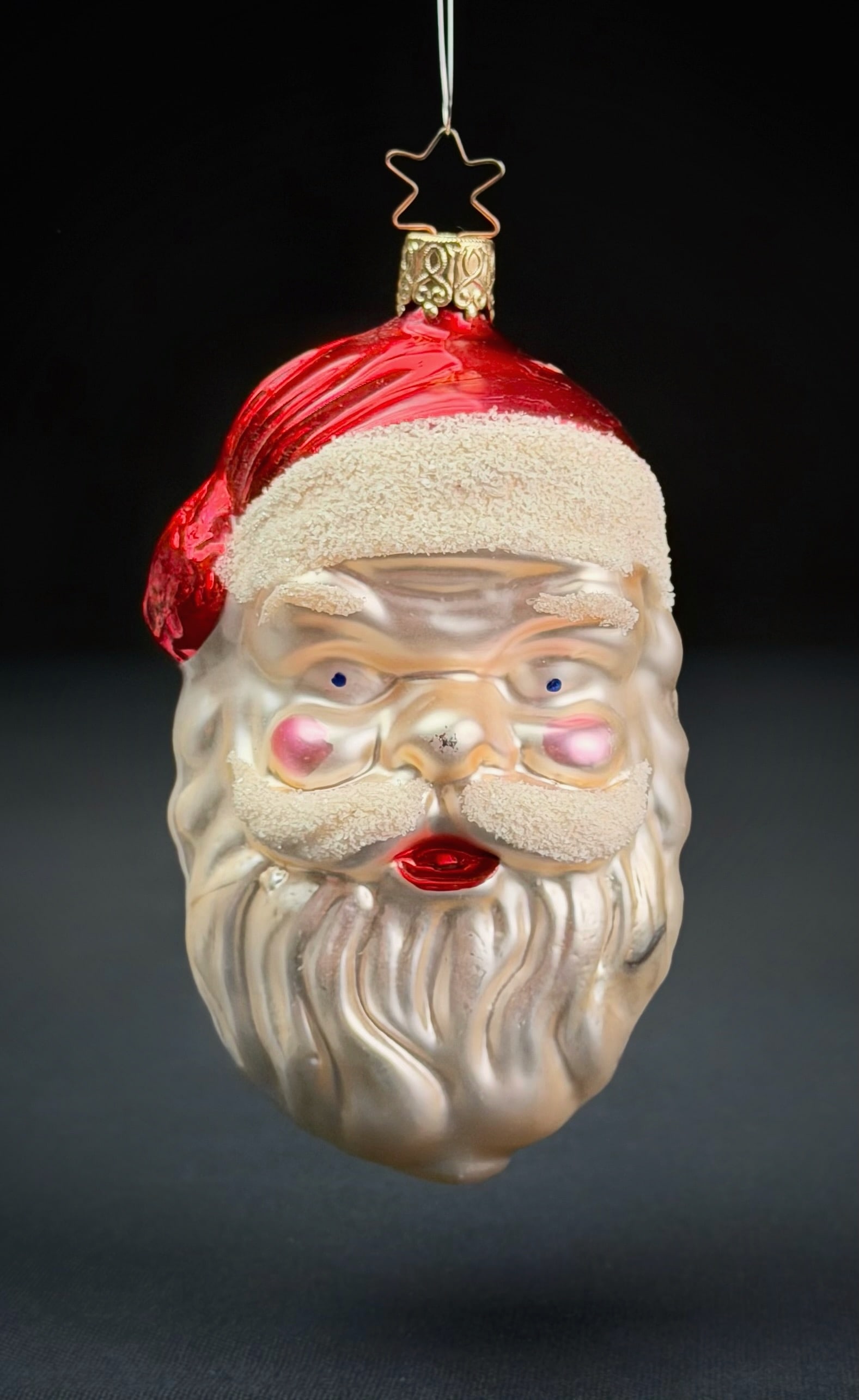 Inge Glas West Germany Santa Head Ornament: A vintage molded glass Christmas ornament depicting the head of Santa Claus. Produced by Inge Glas in West Germany, this piece features a lustrous finish, hand-painted details, and textured accents on