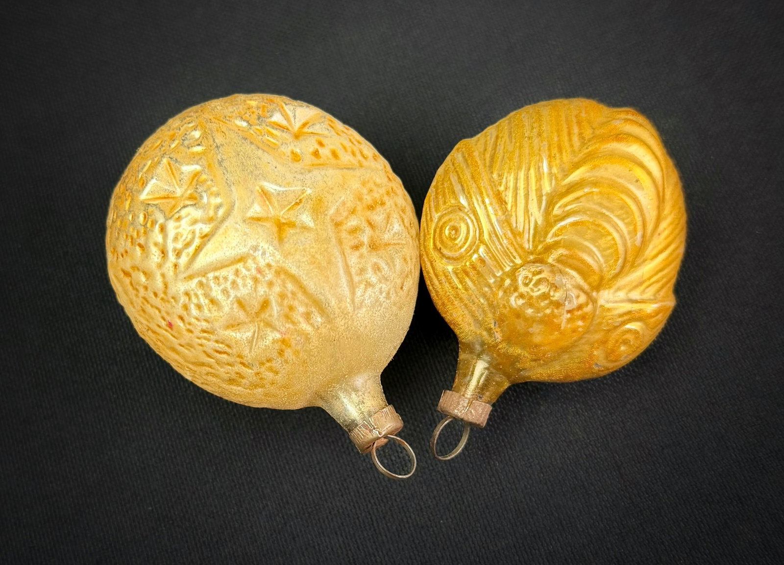Two Antique German Glass Christmas Ornaments: A lot of two mid-century molded glass Christmas ornaments. This group includes a figural rooster head ornament with a gold finish and a round ornament with an embossed star pattern and a frosted gold 
