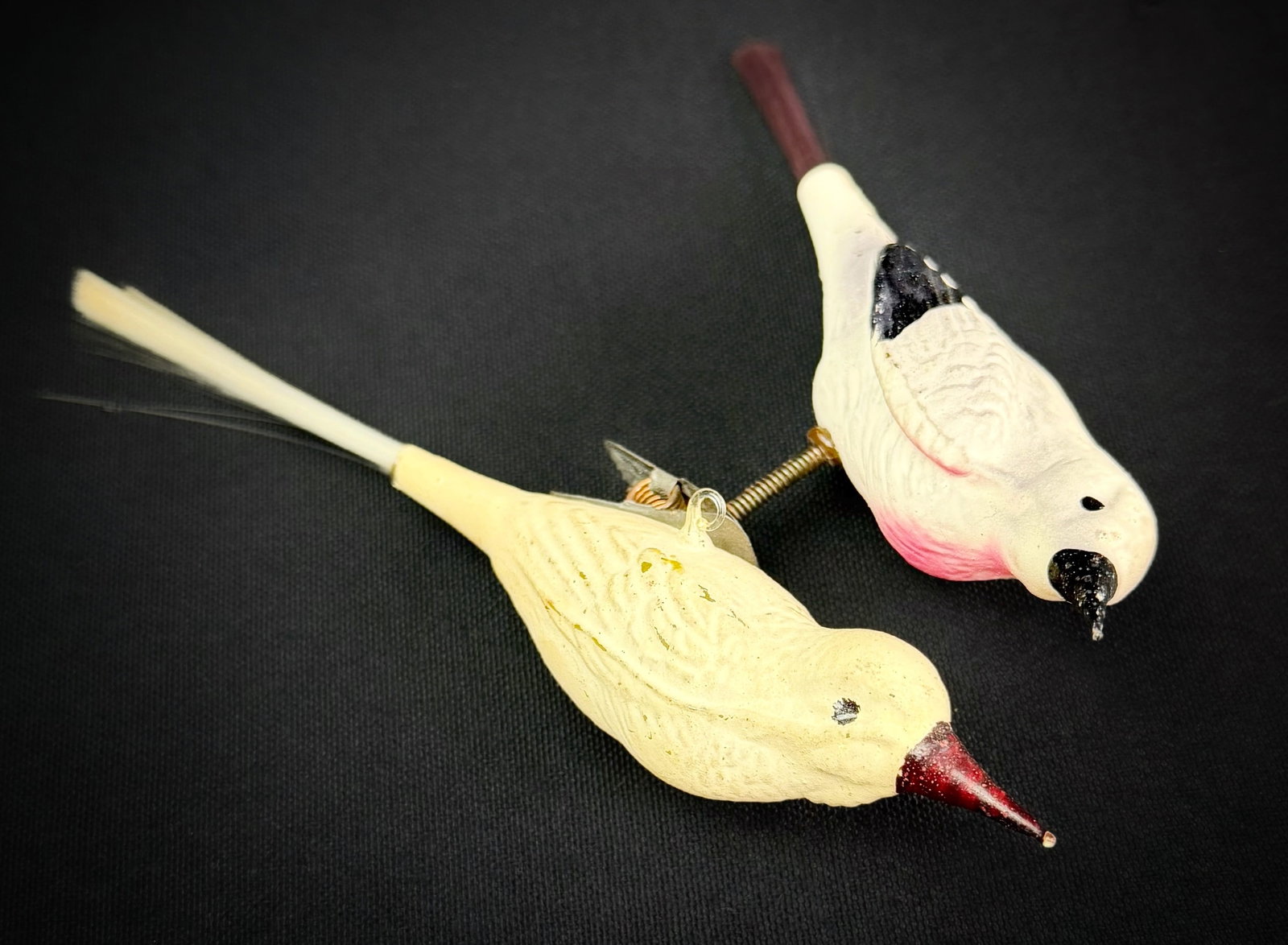 Two Antique German Glass Bird Ornaments: A lot of two antique German glass bird ornaments. One bird is painted yellow with a red beak and features a spun glass tail. The second bird is painted white with pink and black details. Christmas, ho