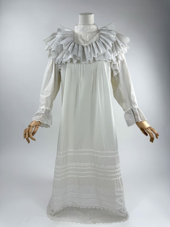 Vintage 1970s does Victorian White Cotton Dress: Vintage 1970s does Victorian White Cotton Eyelet Lace Ruffled Dress. Eyelet lace ruffles through shoulders and neckline with pleats. Closes at back neck with buttons. Pleated with lace details at hem.