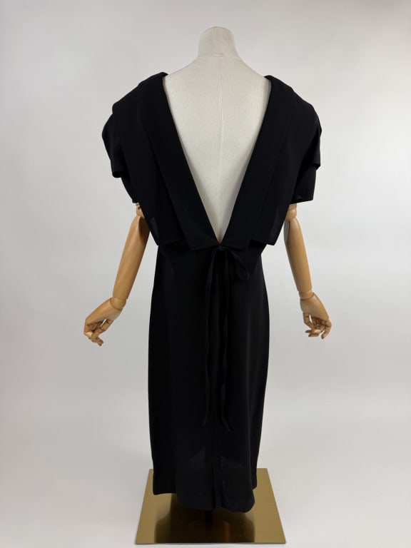 Vintage 1980s Gianni Versace Wool Cocktail Dress: Vintage 1980s Gianni Versace Black Wool Cocktail Dress. With plunging V neckline in back and bow detail. No closures, slides over head. Marked size 46. Measures 40 bust, 38 waist, 45 inches long, 10 i