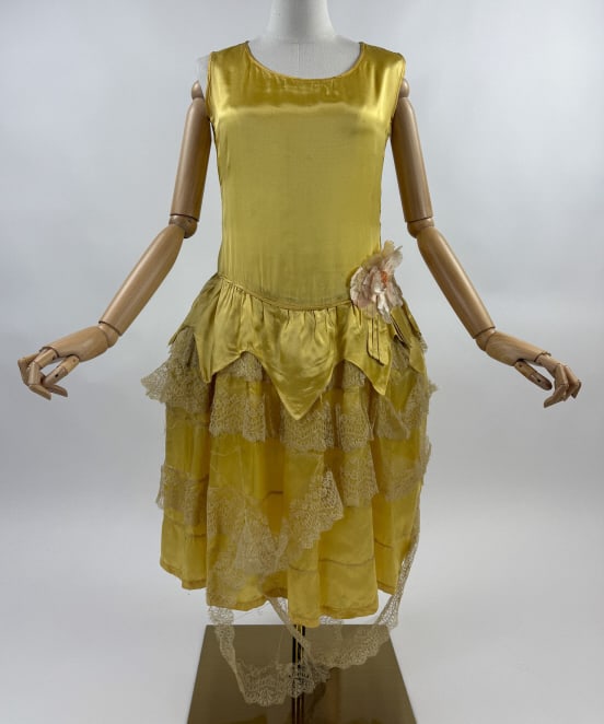 Antique 1920s Yellow Rayon Satin Lace Tiered Dress: Antique 1920s Yellow Rayon Satin Lace Tiered Drop Waist Floral Accent Dress. Closes at side with hooks. Floral detail at waist. Tiered ruffled lace through skirt. Fair antique condition to ruffles and