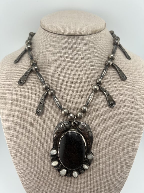 Vintage Native American Sterling Squash Blossom: Vintage Native American Sterling Squash Blossom Necklace. With black goldstone and mother of pearl. Beaded necklace stand measures 23 inches in length. Squash blossom pendant measures just over 2.5