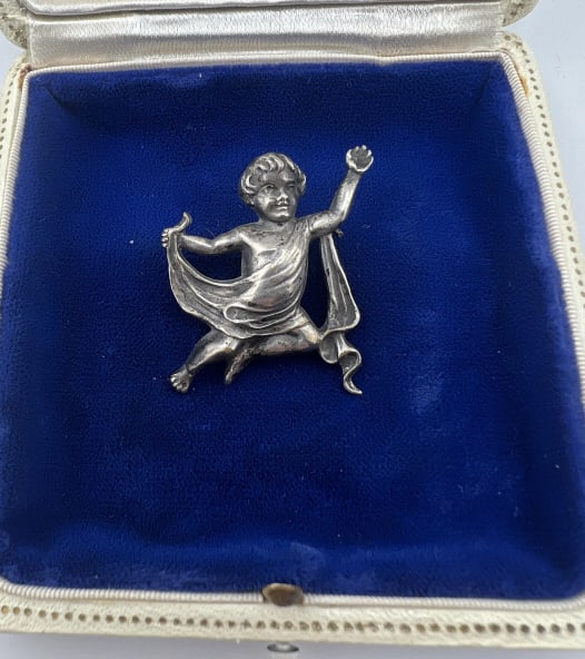 Antique C 1900 Repousse Sterling Cherub Brooch: Antique C 1900 Repousse Sterling Cherub Brooch.Figural sterling silver repousse brooch of a cherubic child with Greco Roman style draping to his vestments. Measures 1.5 by 1.5 inches.