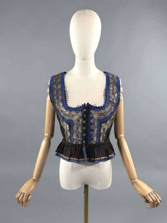 Antique Black Silk & Metal Lame Lace Dirndl Top: Antique Black Silk & Metal Lame Lace Dirndl Top. Buttons at front with green glass buttons & embellished with metal lace. Deep neckline. Fully lined in cotton. Ruched through waist with peplum. Measur