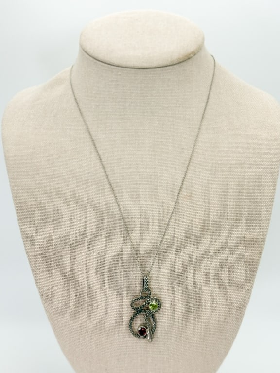 Vintage Sterling Peridot Garnet Snake Necklace: Vintage Sterling Peridot Garnet Snake Pendant Necklace having snake pendant set with garnet and peridot stones. Pendant marked 925, chain marked sterling. Pendant measures approximately 1.5 inches lon