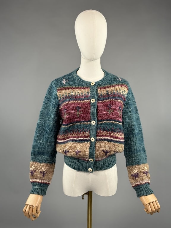 Vintage 1970s Manos del Uruguay Hand Knit Sweater: Vintage 1970s Manos del Uruguay Hand Knit Cardigan Sweater having stripes & florals at front & sleeves and button closure up center front. 100% wool. Measuring 20 inches flat across chest, 21 inches l