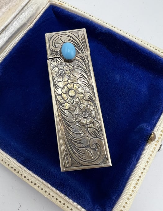 Antique 800 Silver & Turquoise Lipstick Compact: Antique 800 Silver & Turquoise Lipstick Compact.Hand chased floral and scroll work motif lipstick compact set with a turquoise tone glass cabochon clasp. Hallmarked 800. Measures 2.25 inches in length