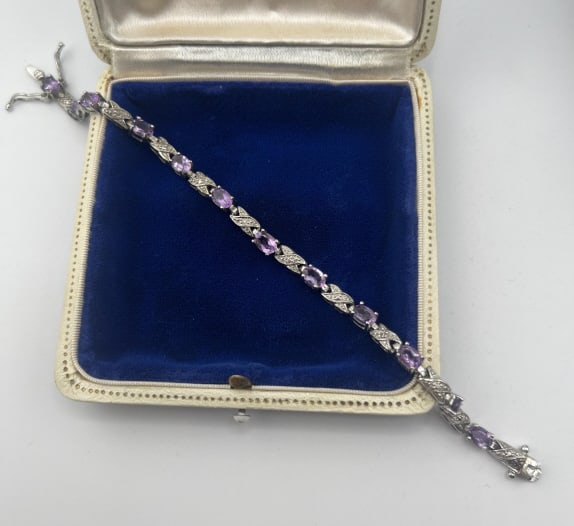 Diamond Amethyst & Sterling Silver Tennis Bracelet: Diamond Amethyst & Sterling Silver Tennis Bracelet. Articulated panel bracelet in sterling silver and set with amethysts and diamond accents. Measures 7.25 inches in length. Hallmarked. Has two safety