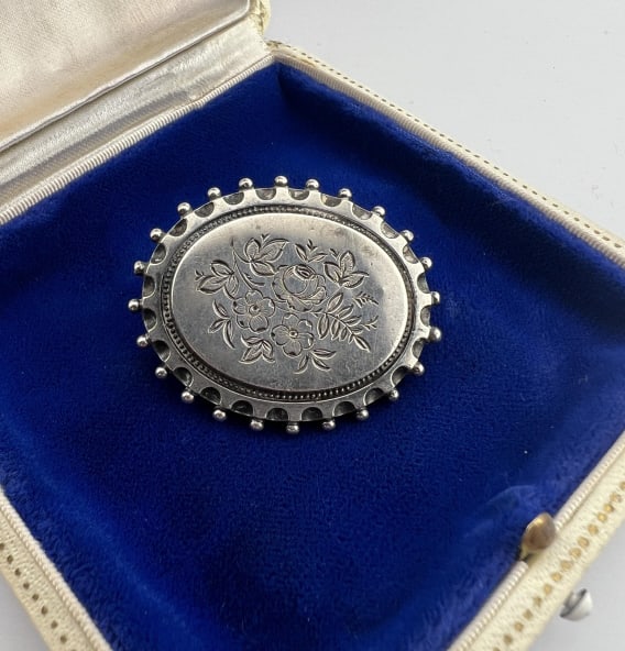Antique 19th C English Silver Floral Motif Brooch: Antique 19th C English Silver Floral Motif Brooch. Back is marked "STANDARD SILVER" and has British registry mark. Front with engraved oval plaque of flowers. Measures just over 1.5 inches in width.