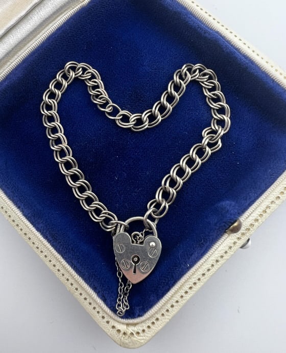 Estate Sterling Curb Link Padlock Clasp Bracelet: Estate Sterling Silver Curb Link Heart Form Padlock Clasp Bracelet. Hallmarked. Has a safety chain. Measures 7 inches in length.