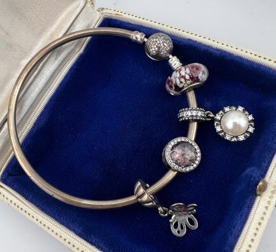 Sterling Silver Pandora Bracelet w Bead Charms: Sterling Silver Pandora Bracelet w Bead Charms. Sterling silver bangle bracelet with four beads / charms and snow flake motif clasp. Signed PANDORA. Hallmarked for sterling. Measures 2.5 inches across