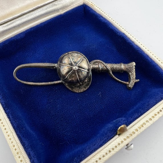 Antique Repousse Sterling Silver Equestrian Brooch: Antique Repousse Sterling Silver Equestrian Brooch. Riding helmet and jockey crop. Hallmarked. Measures 2.5 inches in length.
