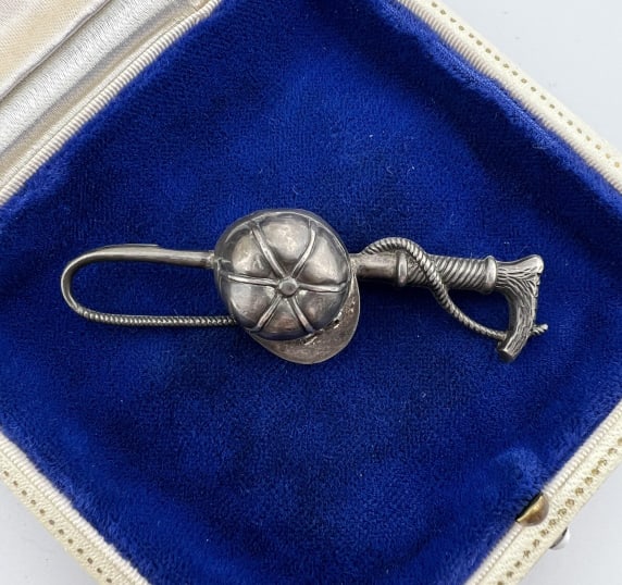 Antique Repousse Sterling Silver Equestrian Brooch: Antique Repousse Sterling Silver Equestrian Brooch. Riding helmet and jockey crop. Hallmarked. Measures 2.5 inches in length.