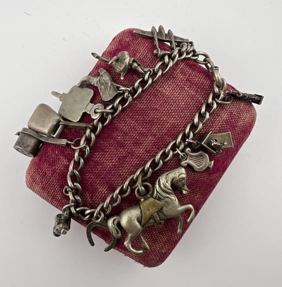 Antique Sterling Charm Bracelet w Charm Collection: Antique Sterling Silver Charm Bracelet w Charm Collection. Curb link bracelet with charms including; statue of liberty, bird house, horse, horse shoe, musician, pot, bell, school charm, cow boy boot,