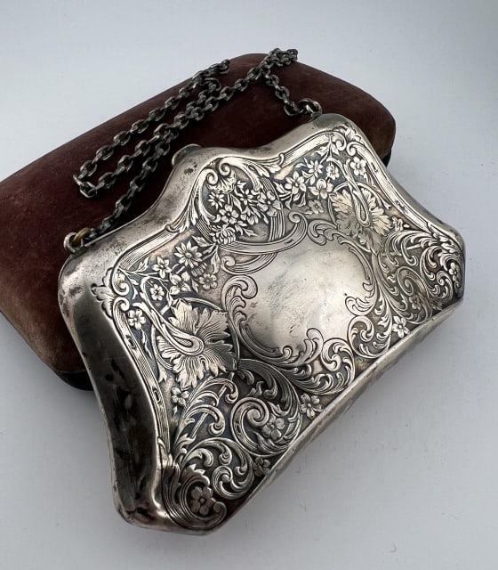 Antique Art Nouveau C 1900 Sterling Silver Purse: Antique Art Nouveau C 1900 Sterling Silver Purse. Floral and scrollwork motif to the exterior. Interior is stamped STERLING. Weighs approximately 70 grams. Purse portion measures 4.5 x 2.75 inches.