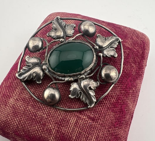 Antique Sterling & Green Onyx Arts & Crafts Brooch: Antique Sterling & Green Onyx Arts & Crafts Brooch. Set with a green onyx cabochon at center in leaf motif. Measures 2 inches in width.