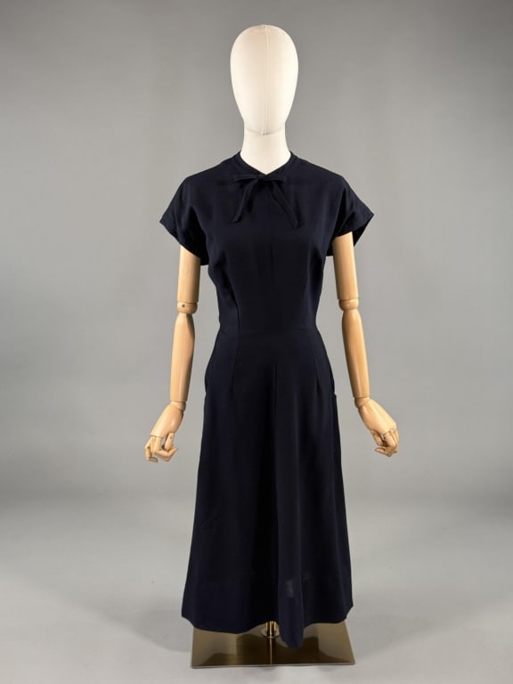 Vintage 1950s Pauline Trigere Wool Crepe Day Dress: Vintage 1950s Pauline Trigere Wool Crepe Day Dress having bow detail and neck, fitted throughout, with pockets at hips and center back zip closure. Light wear as shown specifically under arms with sma