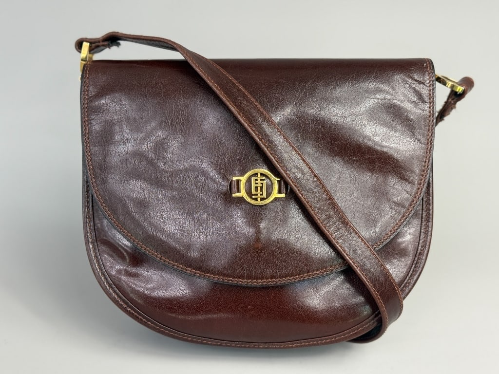 Vintage Emilio Pucci Brown Leather Shoulder Bag: Vintage Emilio Pucci Brown Leather Shoulder Bag having gold tone monogram hardware at front with snap closure, interior zippered pocket and long shoulder strap. Measuring approximately 9 inches wide 7