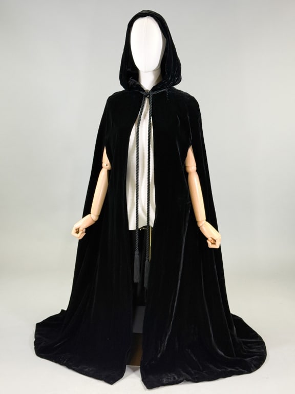 Vintage 1970s Mollie Parnis Velvet Opera Cape: Vintage 1970s Mollie Parnis Black Velvet Opera Cape Shawl having corded fringe tie and hook at neck with hood. Labeled Mollie Parnis Boutique New York. One size fits most, measuring 52 inches long. Ge