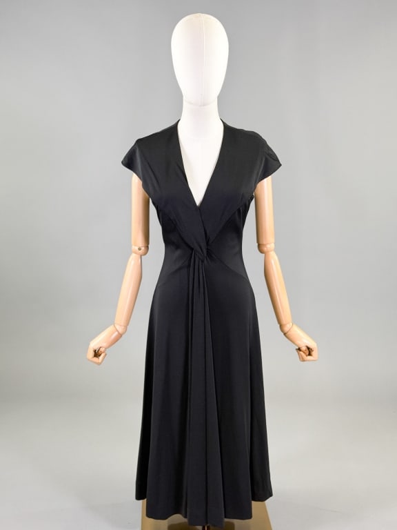 Vintage 1970s Estevez Jersey Knit Draped Dress: Vintage 1970s Estevez Jersey Knit Draped Dress having v-neckline with draped details at front, closing at center back with zip. Labeled Estevez. Measuring 34 - 40 inch bust, 26 - 36 inch waist, 44 inc
