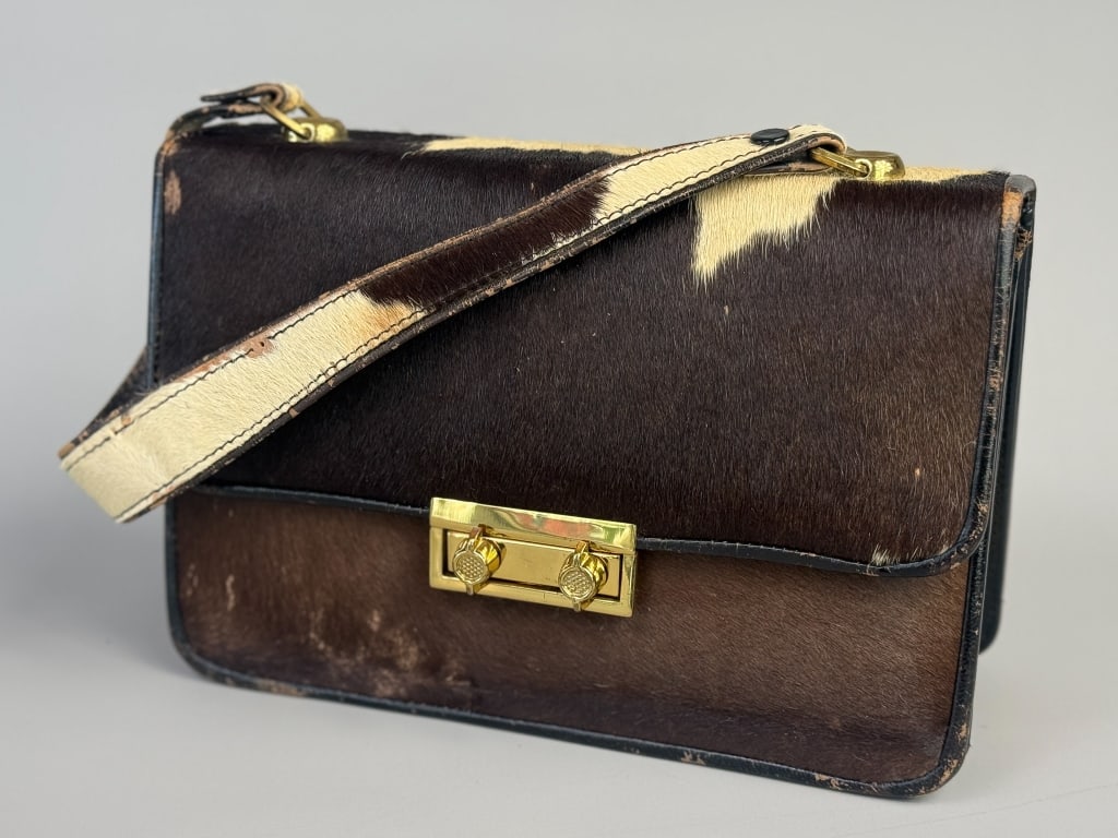 Vintage 1960s Cowhide Leather Box Hand Bag: Vintage 1960s Cowhide Leather Box Hand Bag having gold tone lock closure at front. Measuring approximately 9.5 inches wide by 6.5 inches tall by 3.5 inches deep with a 7.5 inch strap drop. General wea