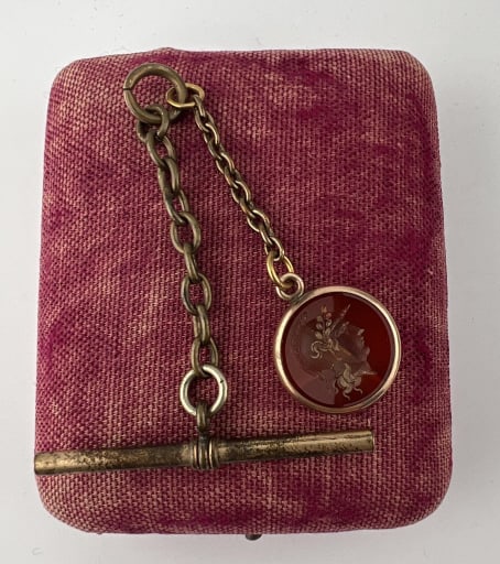 Antique 19th C Carnelian Intaglio Fob Pendant: Antique 19th C Carnelian Intaglio Fob Pendant on Chain w T Bar. Greco Roman style carved intaglio fob pendant in bezel gold filled setting. Measures approximately 2.5 inches in length bail to T bar.