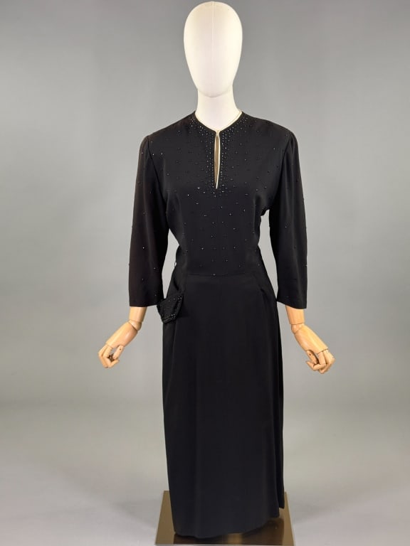 Vintage 1940s Black Crepe Metal Studded Dress: Vintage 1940s Black Crepe Metal Studded Dress having studs throughout with hook closure at neck, side zip and one pocket at front. Labeled C.H.D. Robbins. Measuring 40 inch bust, 30 inch waist, 48 inc