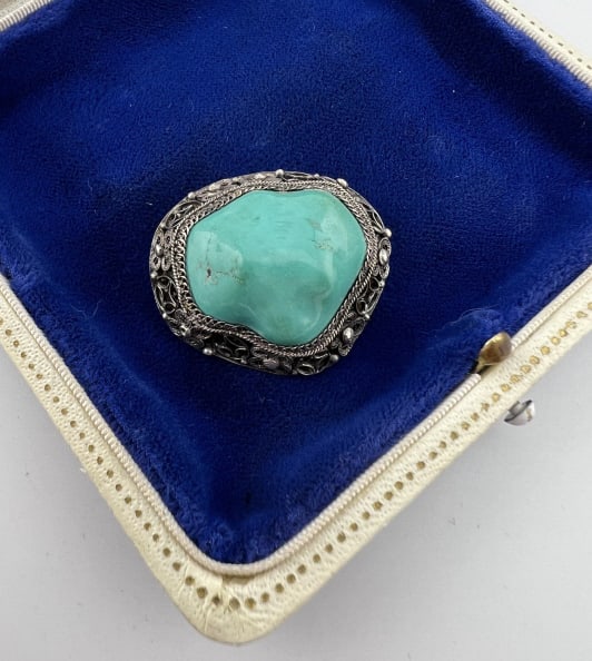 Vintage Chinese Filigree Silver & Turquoise Brooch: Vintage Chinese Filigree Silver & Turquoise Brooch. Stamped SILVER on the back. Set with a tumbled and polished turquoise at center. Likely Chinese in origin. With floral motif pattern. Measures 1.25 