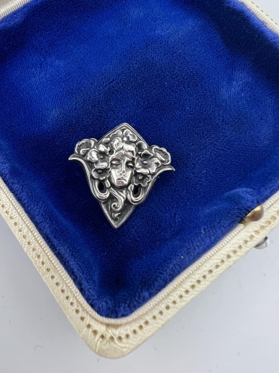 Antique C 1900 Art Nouveau Sterling Silver Brooch: Antique C 1900 Art Nouveau Sterling Silver Brooch. Repousse scene of a lady in the Art Nouveau fashion surrounded by flowers. Back is marked STERLING FRONT. Measures 1 inch in length.
