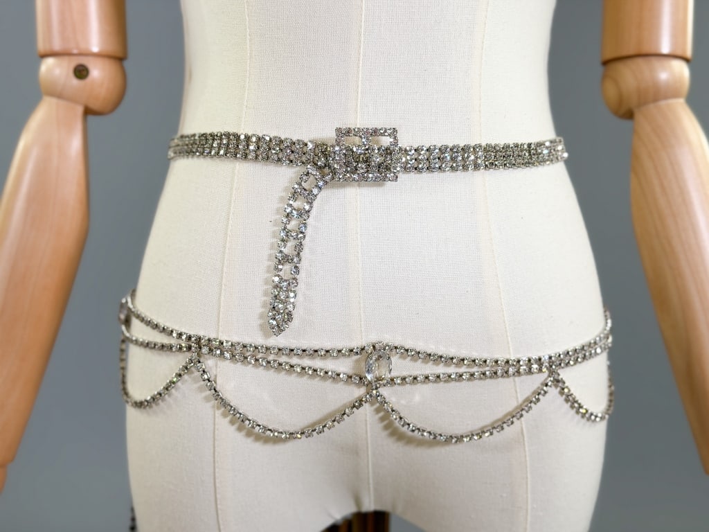 Two Vintage Rhinestone Metal Belts: Two Vintage Rhinestone Metal Belts. One having festoon detail with adjustable waist size and one with rhinestone buckle. Rhinestone buckle belt measuring 27.5-31.5 inch waist, 32 inches total length. 
