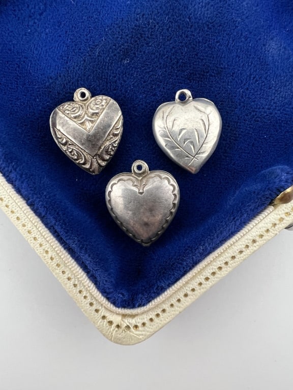 Three Antique Sterling Silver Puffy Heart Charms: Three Antique Sterling Silver Puffy Heart Charms / Pendants. Hallmarked or stamped on each STERLING. Each over 1/2 an inch in length, approximately 5/8ths of an inch each.