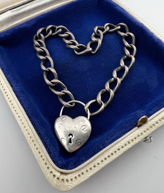 Sterling Silver Curb Link Bracelet w Padlock Clasp: Sterling Silver Curb Link Bracelet w Padlock Clasp. Heart form padlock design sterling silver clasp, arched portion at the top opens. Chain acid tests for sterling, clasp is hallmarked. Measures