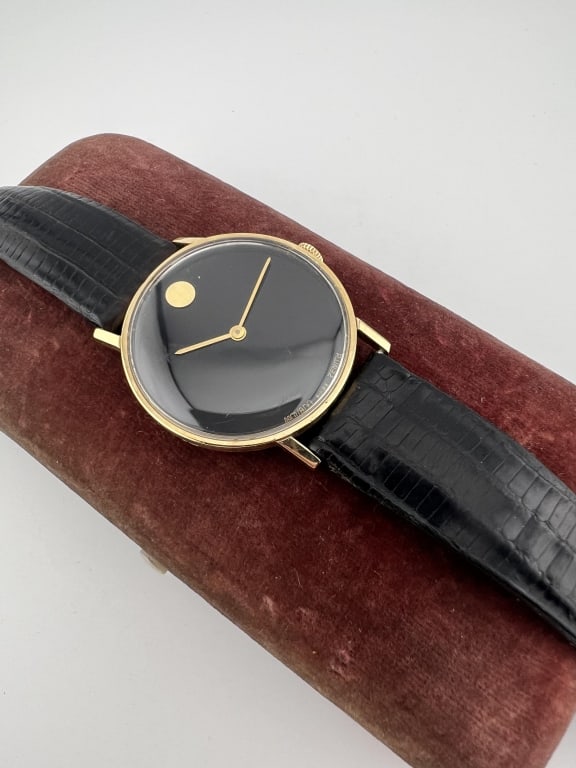 14kt Yellow Gold Movado Vintage 1970s Watch: 14kt Yellow Gold Movado Vintage 1970s Watch. Hallmarked on the back of the case. Face is signed. Leather band. Face measures approximately 1.25 inches in diameter. Black background with gold hands and
