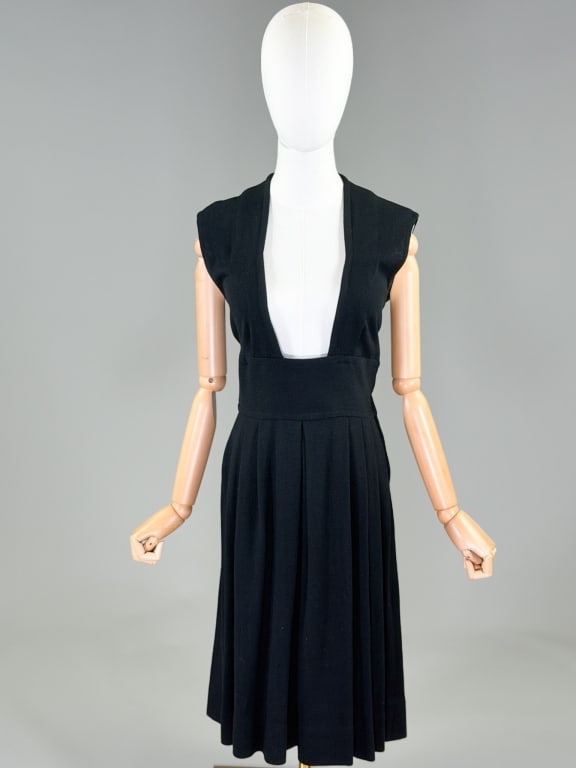 Vintage 1950s Black Wool Pinafore Dress: Vintage 1950s Black Wool Pinafore Dress having deep neckline with side zip closure and pleated skirt. Measuring 36-40 inch bust, 28 inch waist, 42 inches long. From the lifetime collection, fashion ar