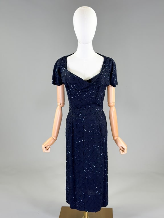 Vintage 1950's Crepe Ruth McCullock Beaded Dress: Vintage 1950's Crepe Ruth McCullock Beaded Dress having shelf bust and beading throughout with side zip closure. Measuring 36 inch bust, 26 inch waist, 43 inches long, 7 inch sleeve length. General we