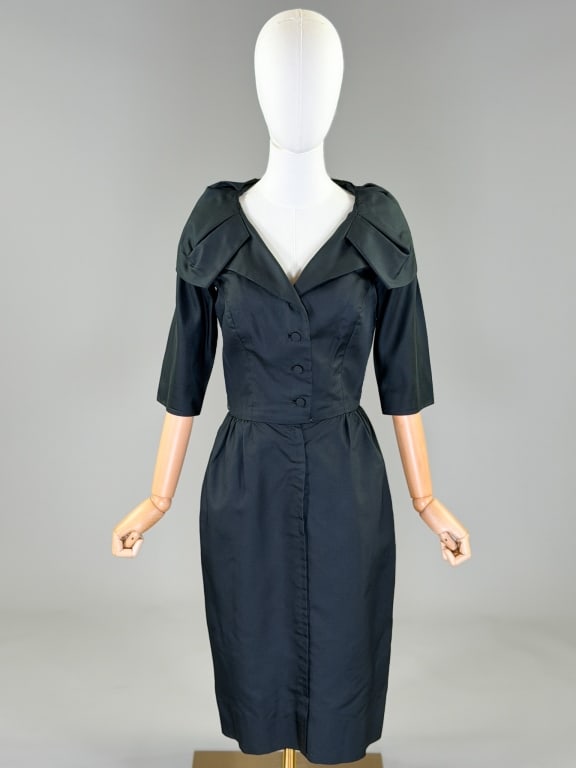 Vintage 1960s Saks Fifth Ave Silk Cocktail Dress: Vintage 1960s Saks Fifth Avenue Silk Cocktail Dress having shawl collar at neck with button and zip front closures. Labeled Saks Fifth Avenue. Measuring 36 inch bust, 28 inch waist, 42 inches long, 12