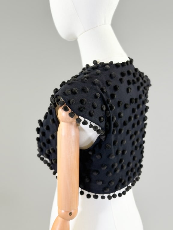 Vintage Black Crepe Velvet Pom Pom Bolero Top: Vintage Black Crepe Velvet Pom Pom Bolero Top having open front and cap sleeves. Measuring 12 inches long. From the lifetime collection, fashion archive and business inventory of collector and dealer