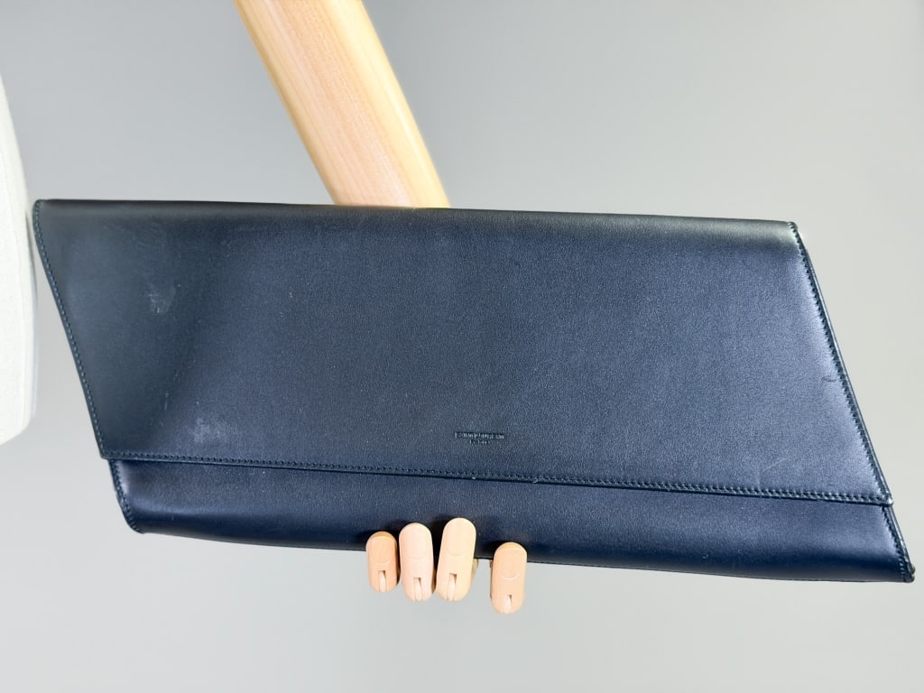 Saint Laurent Paris Leather Clutch Bag Purse: Saint Laurent Paris Leather Clutch Bag Purse having magnetic snap closure with interior pocket. Dust bag included. Measuring approximately 6 inches high by 15 inches wide by 1.5 inches deep. From the 