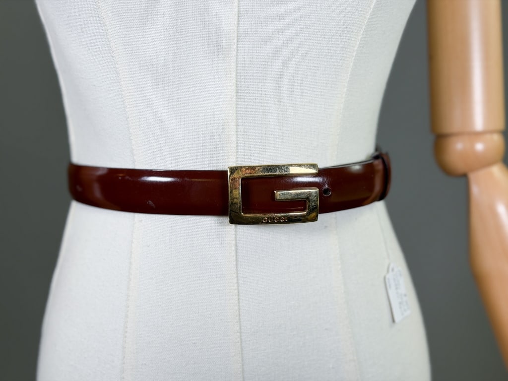Vintage 1990s Patent Leather Gucci Waist Belt: Vintage 1990s Patent Leather Gucci Waist Belt having G logo metal buckle. Marked size 28. Measuring approximately 33 inch total length. General wear as shown throughout. From the lifetime collection, 