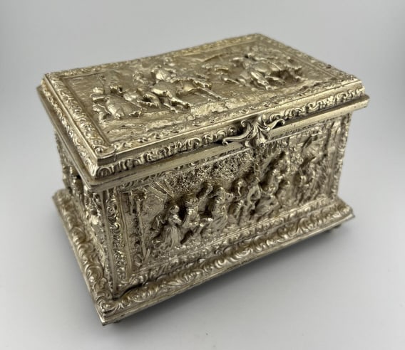 Antique 19th C Silver Box w Silk Tufted Interior: Antique 19th C Silver Box w Silk Tufted Interior. Silver plate jewelry or table box with high bas relief designs on lif and surrounding sides. Interior with tufted red silk. Measures approximately 3.7