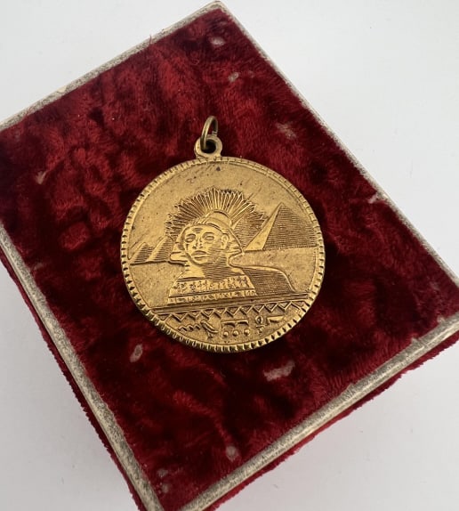 Antique Egyptian Revival Double Sided Pendant: Antique Egyptian Revival Double Sided Pendant. Necklace pendant with scene of Sphinx and pyramid on one side, other side with figure and hieroglyphics. Measures just over 1.5 inches in length.
